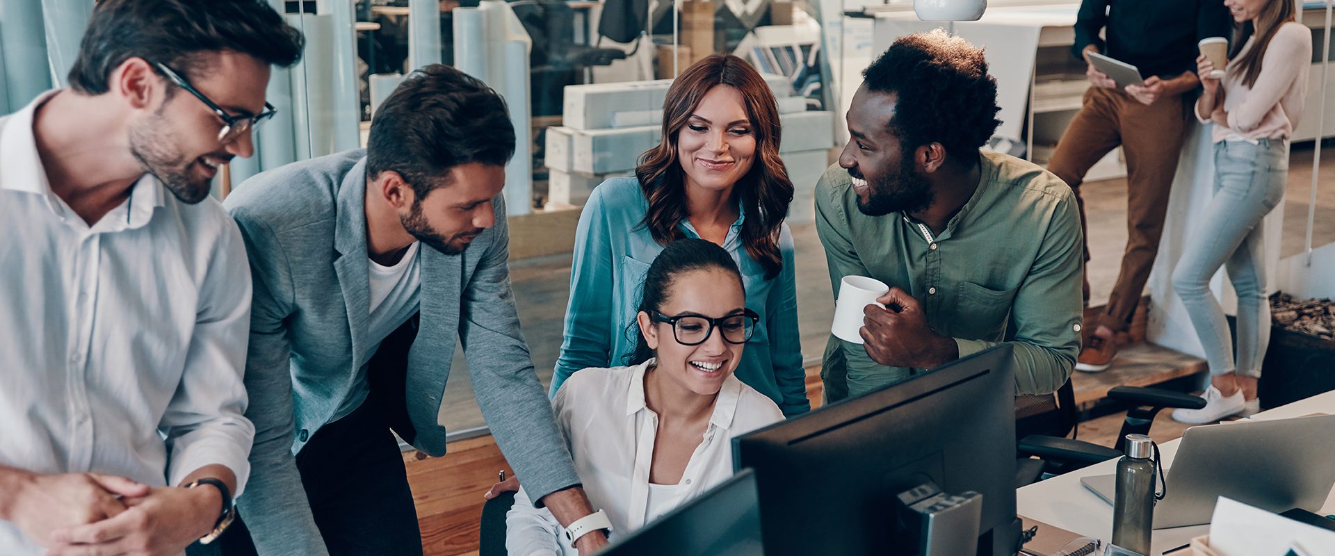 A professional office team collaborating around computers.