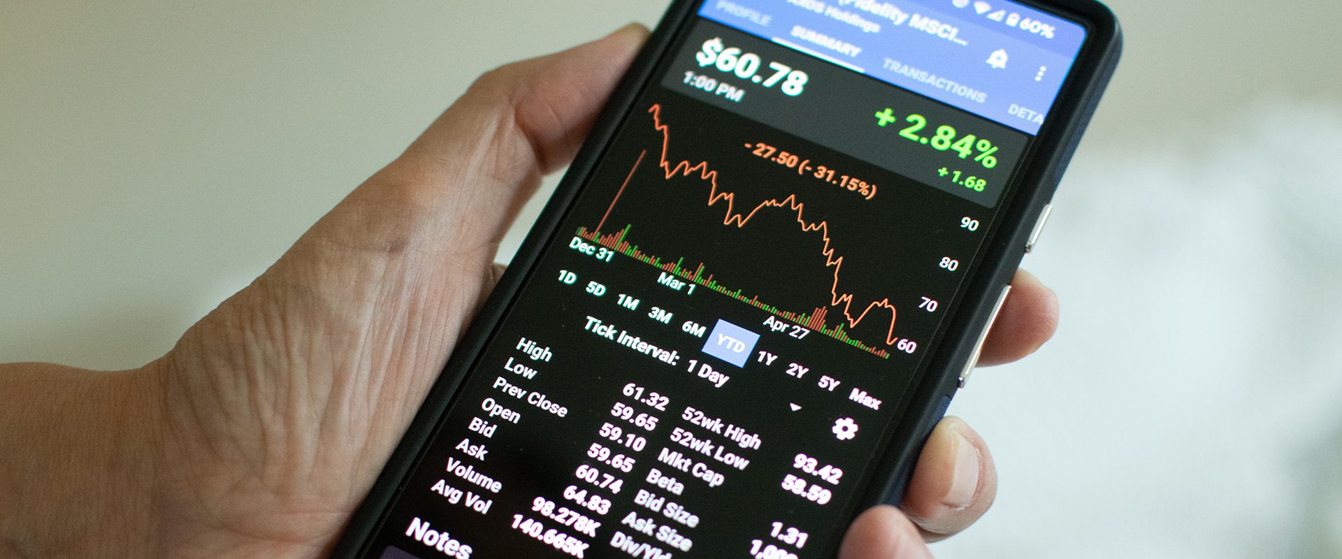 Hand holding a phone displaying a financial app.