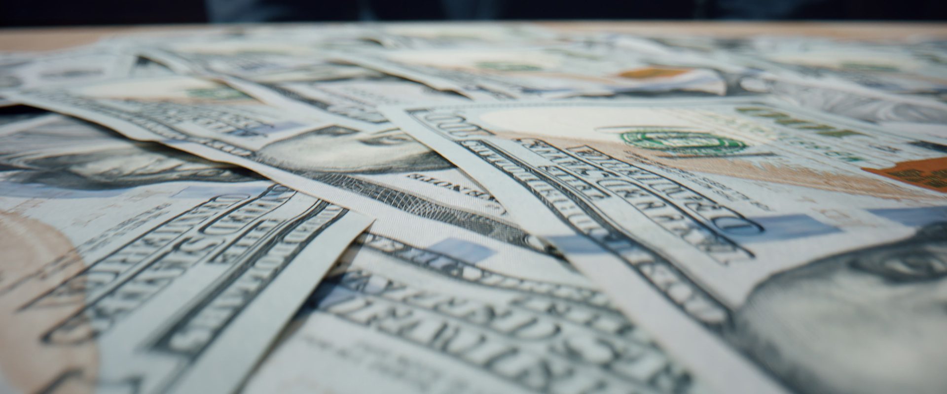 A close-up of USD notes laid flat on a desk.