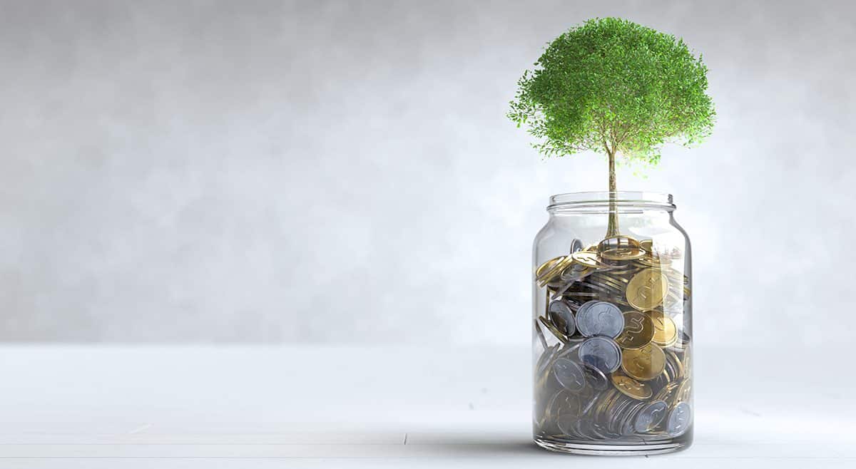 Glass with money and tree growing out, symbolizing growth.